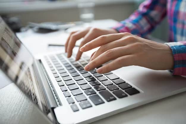 A person in a plaid shirt works at a computer